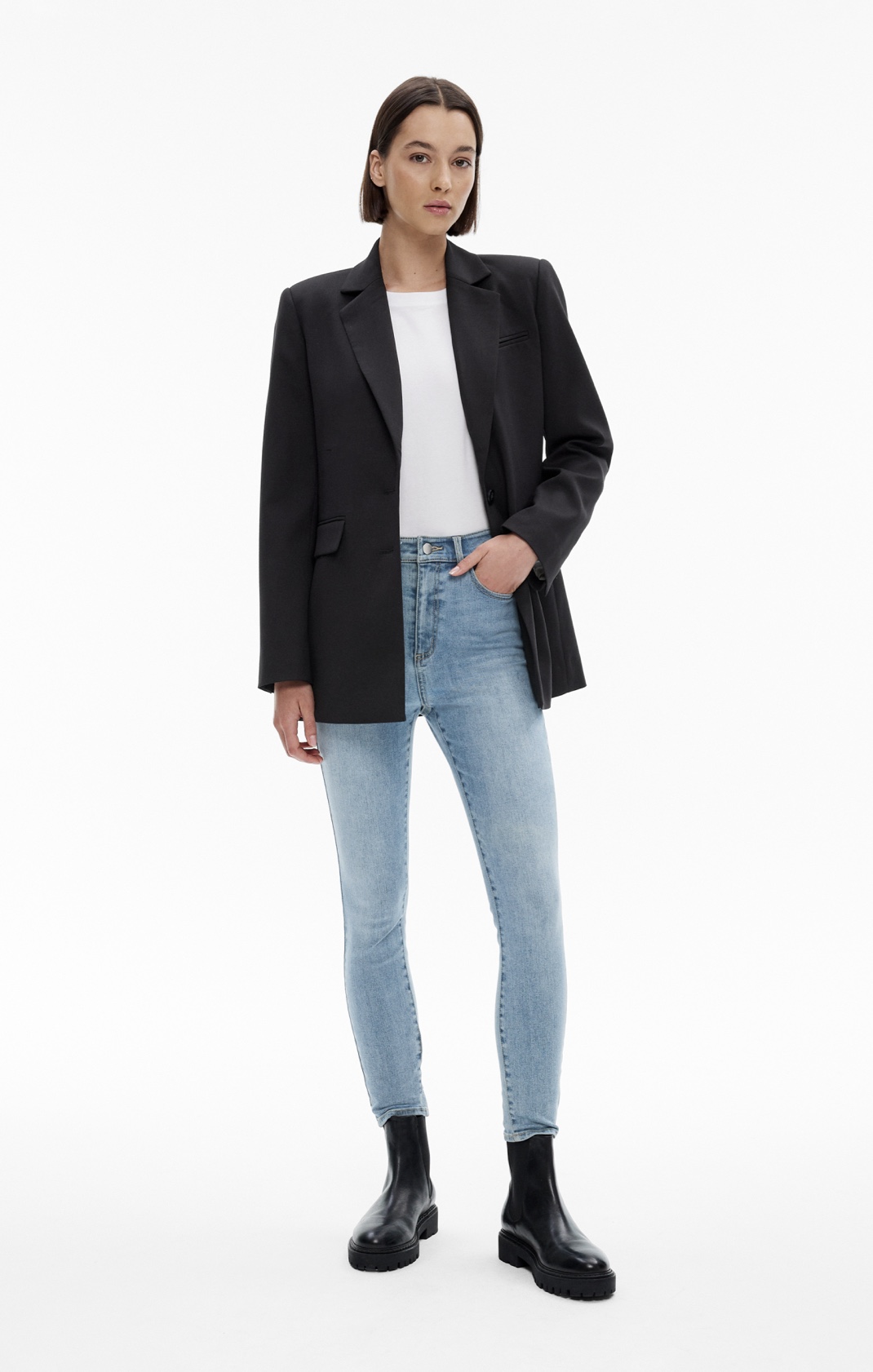 Woman in black blazer, white t-shirt, denim jeans and black boots