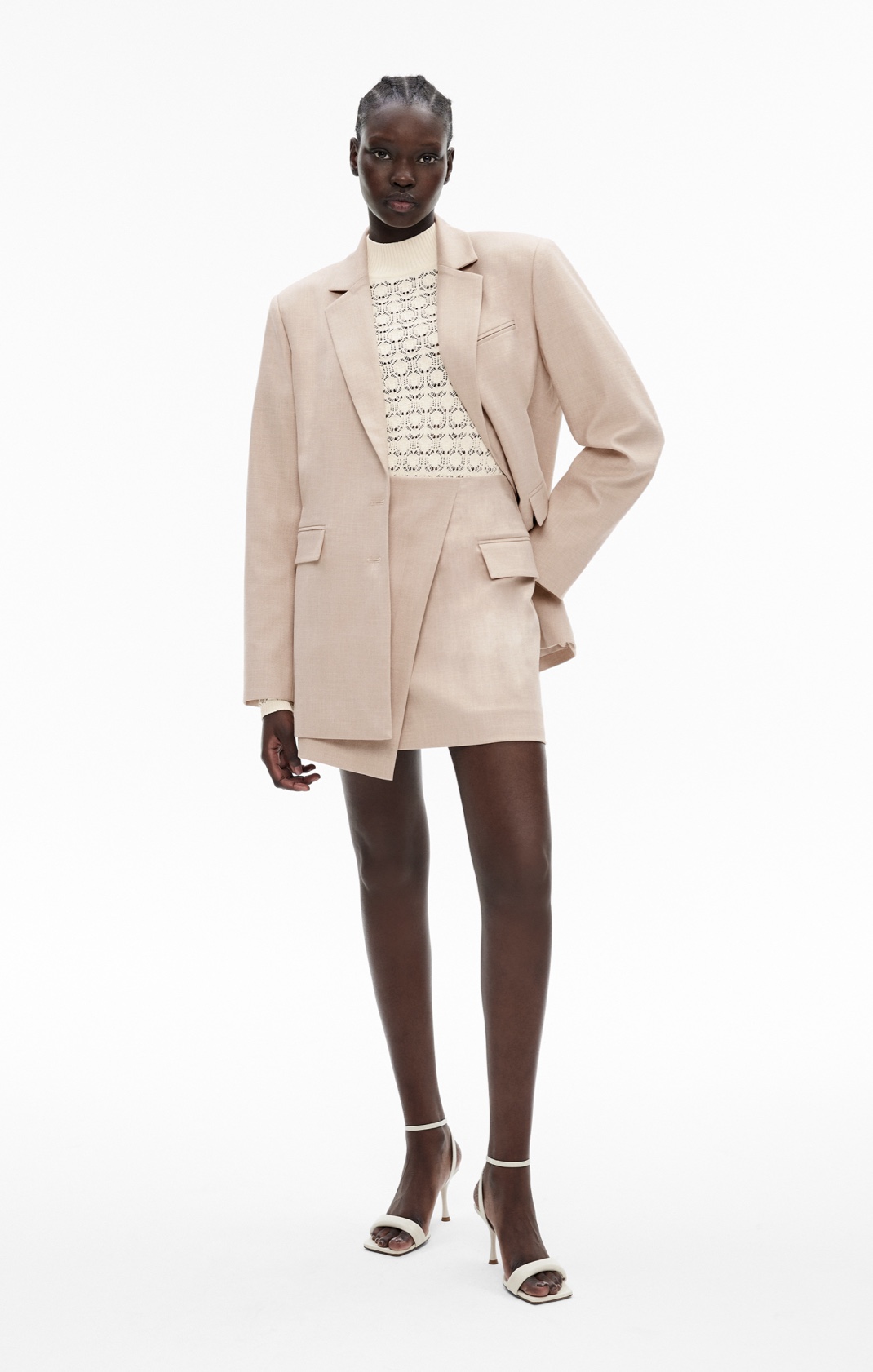 Woman in flax blazer, cream knit top and flax mini skirts
