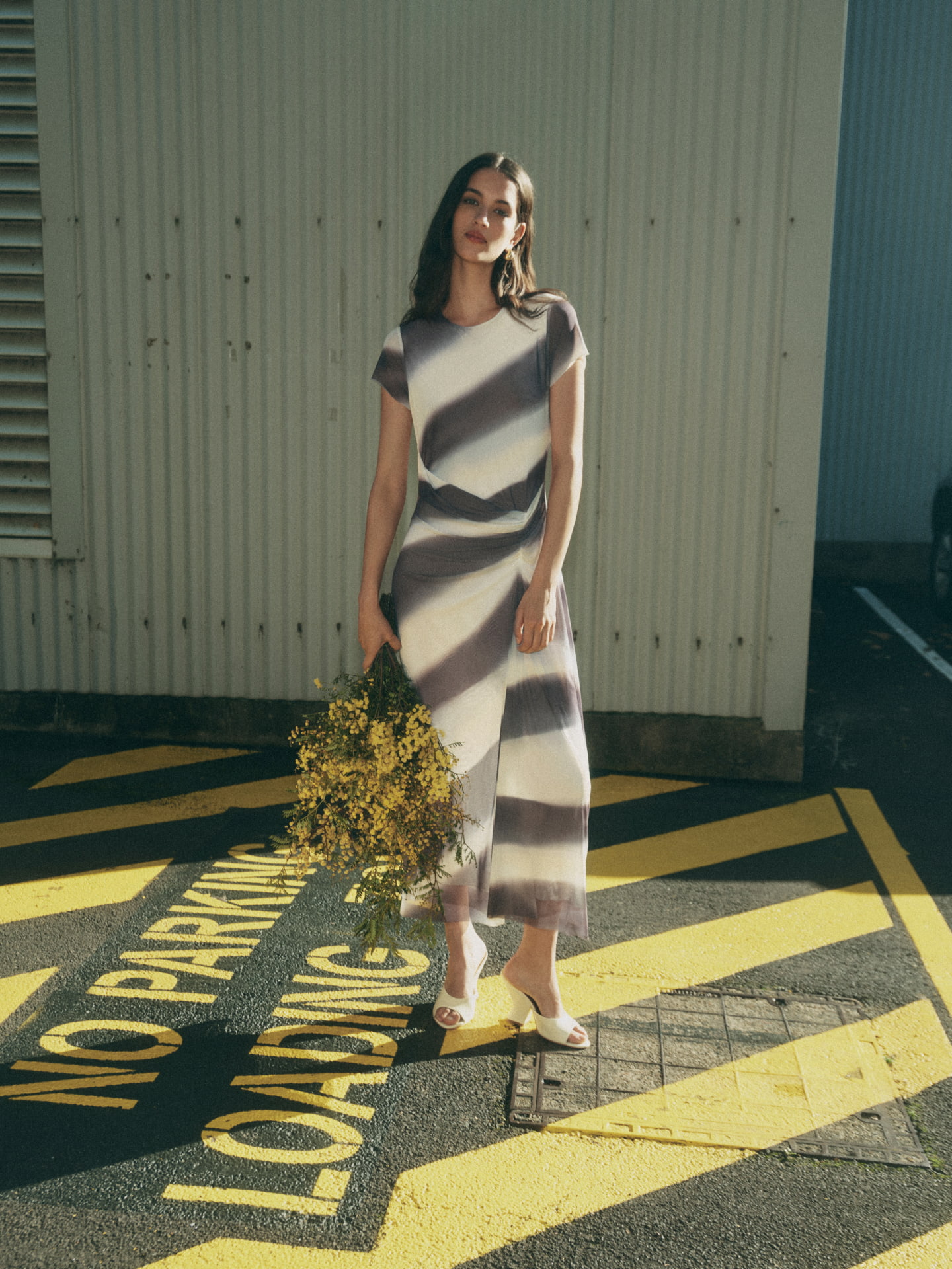Woman wearing the eclipse blue lunar mesh dress, lemon thalia block heel and gold mila pearl stud earrings