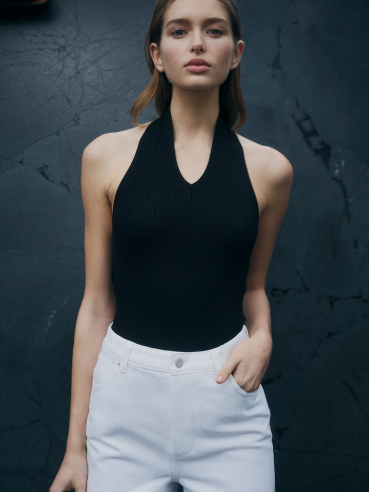 Woman in black halter neck knit, white white high rise wid leg jean, black michelle flats and black liv mini leather bag