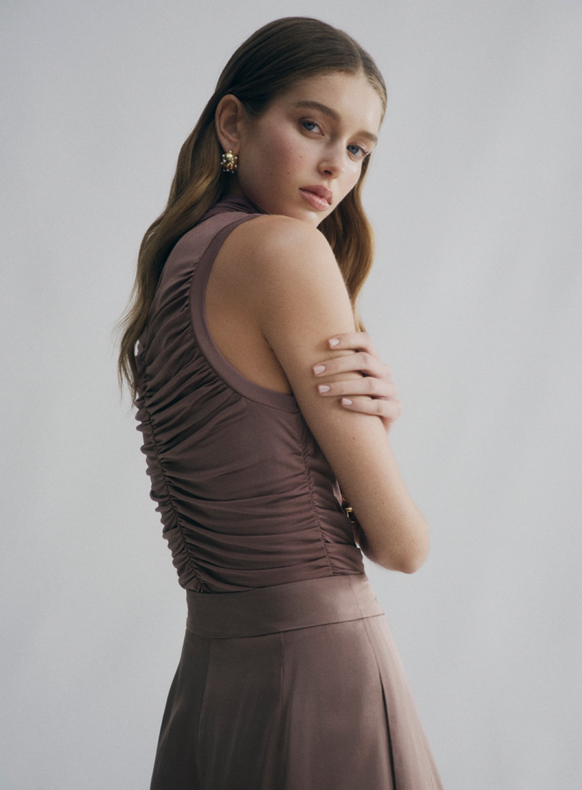 Woman in brown high neck gather top and brown pleat fluid pant