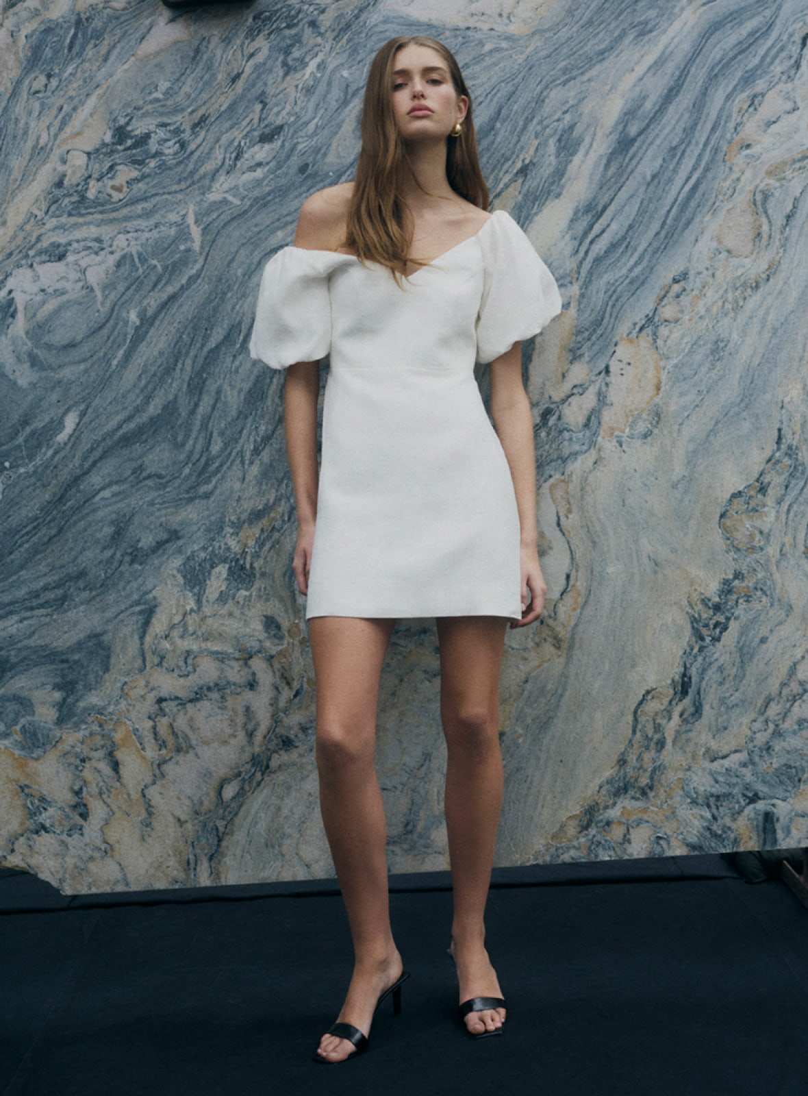 Woman in white wide neck mini dress and blakc grace mule